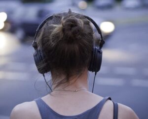 binaural, Industrie du podcast - une femme écoute au casque dans la rue - Festival Entendez-Voir 2023